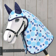 Pláštěnka Bubbles od Hobby Horse LarDen na bílém Hobby Horse s černou uzdečkou, modrýma ušima a světle modrou puntíkovanou dekou s doplňky do každého počasí, na dřevěné tyči před dřevěnou stěnou.