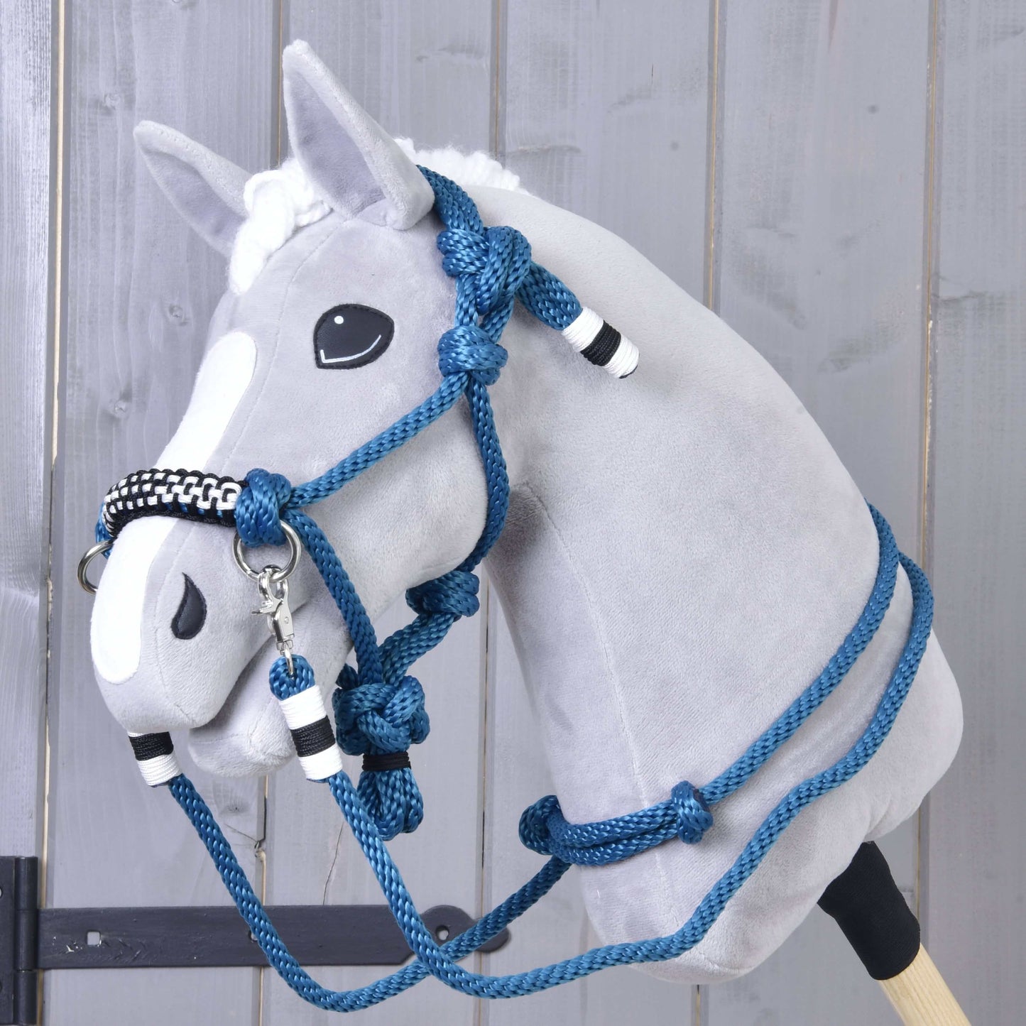 Provazový set Chess od Hobby Horse LarDen na plyšovém Hobby Horse se šedou hlavou, bílou lysinou a modrým cordeo s ohlávkou a otěžemi s černobílými akcenty, před dřevěnou stěnou.