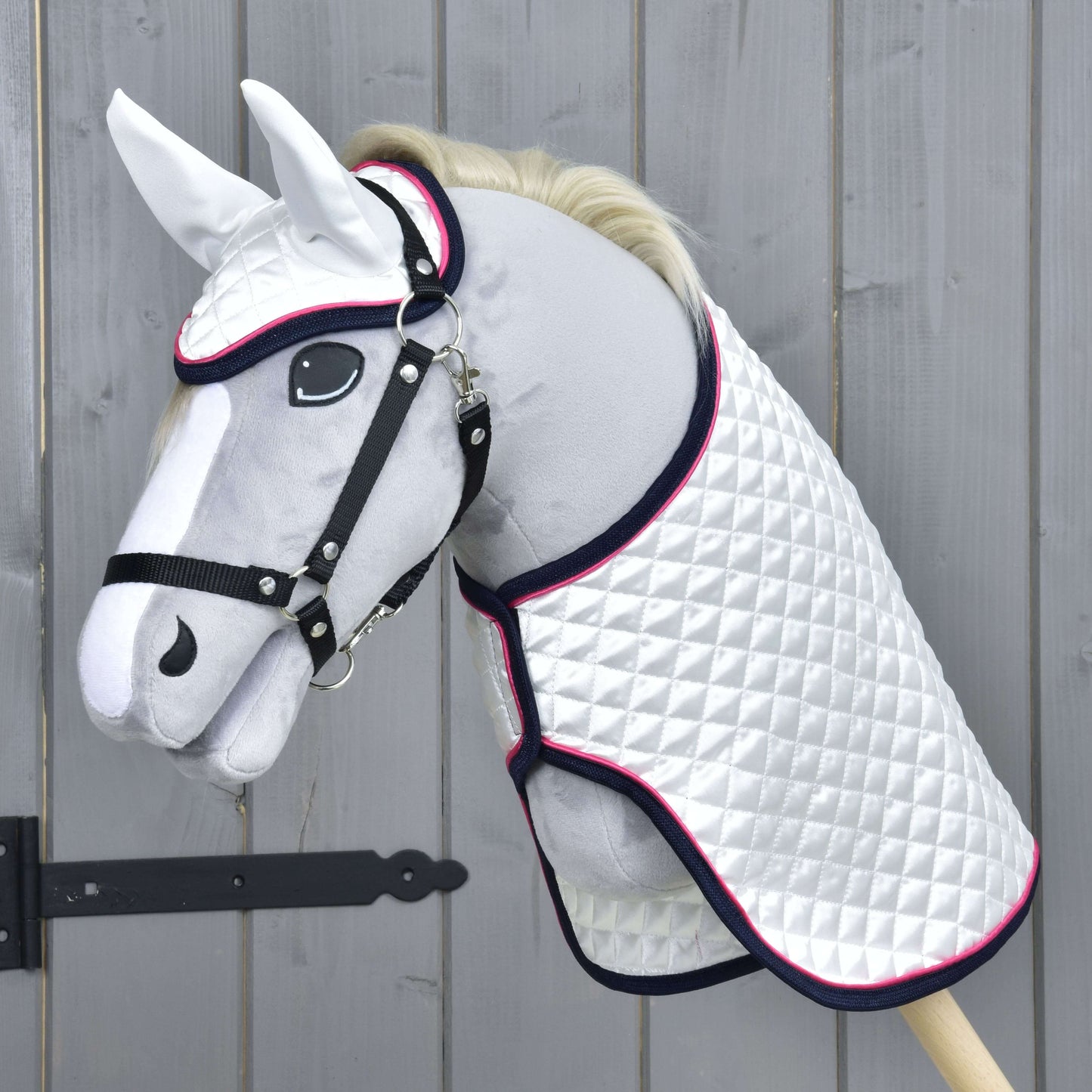 Set Beautiful Star od Hobby Horse LarDen zahrnuje plyšovou hračku Hobby Horse s bílou prošívanou dekou, černou uzdečkou a sadou čabraky, stojící u dřevěného plotu pro stylovou a chráněnou imaginativní hru.