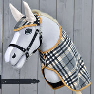 Hobby Horse LarDen Set England Grey se šedým plyšovým Hobby Horse, černou uzdečkou a otěžemi, kostkovanou dekou a ladící čabrakou, vytvářející půvabnou dekoraci na dřevěném pozadí.