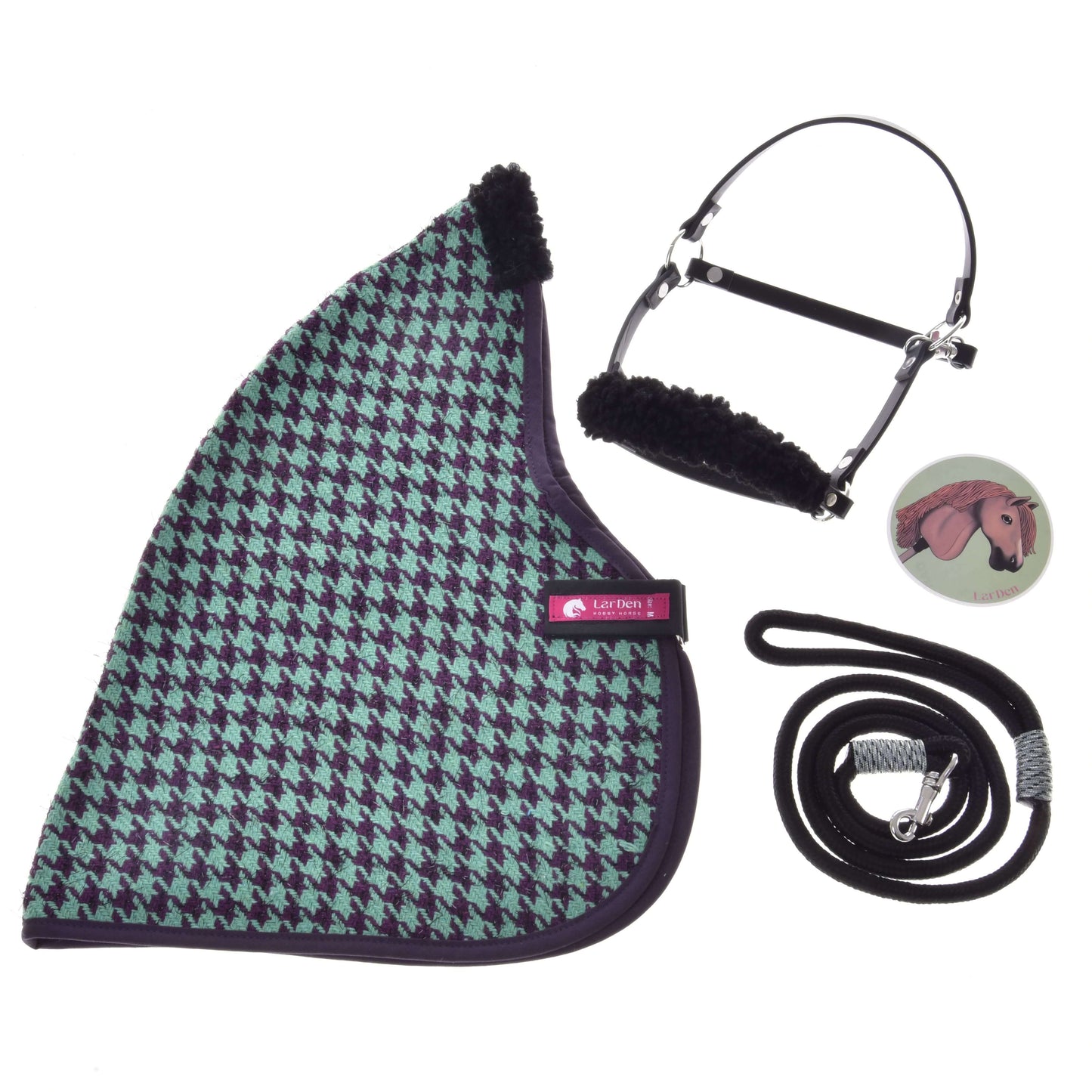 Set Harmony Green od Hobby Horse LarDen rozložený naplocho: zeleno-černá stájová deka se vzorem kohoutí stopy, černá ohlávka s fleecovým polstrováním, černé vodítko se stříbrnou karabinou a kulatý odznak s ilustrací koně.
