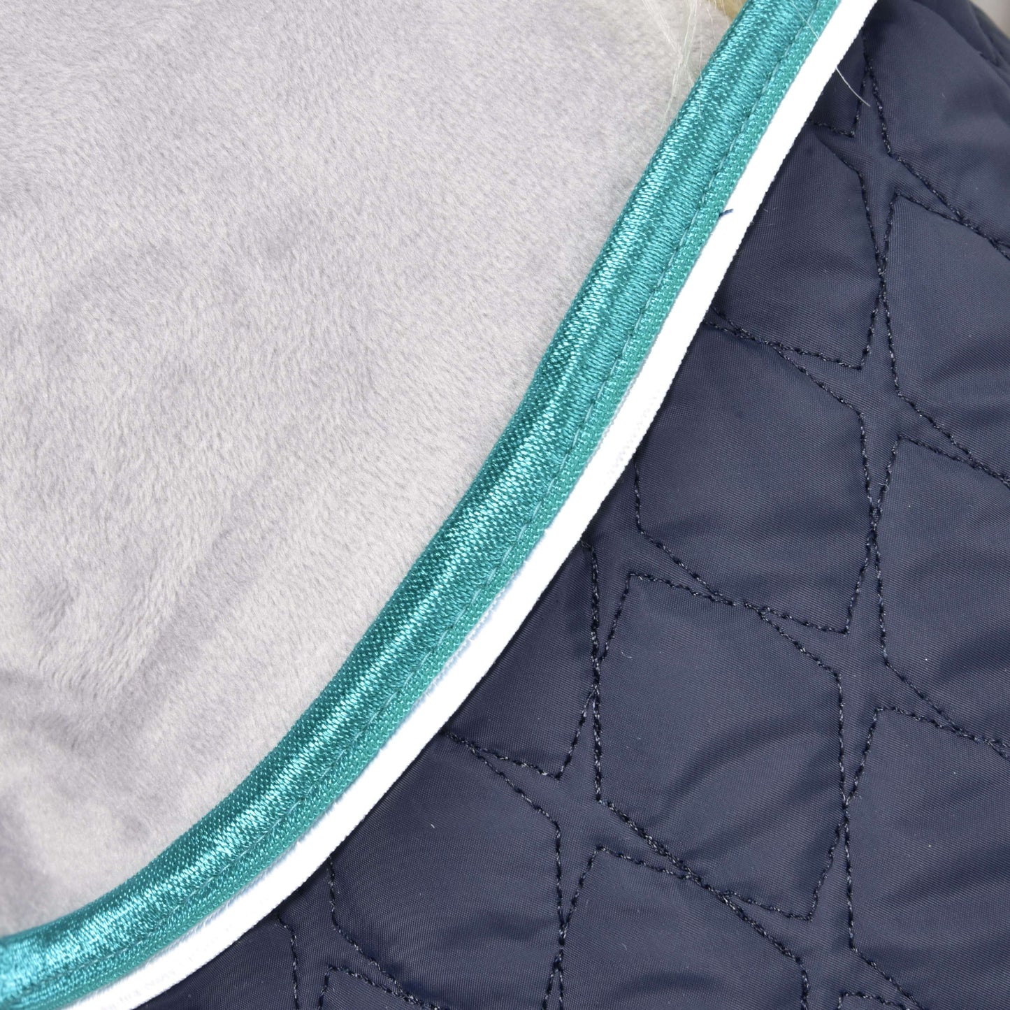 Detail deky Set Supreme Turquoise od Hobby Horse LarDen s prošívanou tmavě modrou látkou s geometrickým prošitím, tyrkysovým lemem a bílou paspulkou – ideální k ochraně vašeho koně.