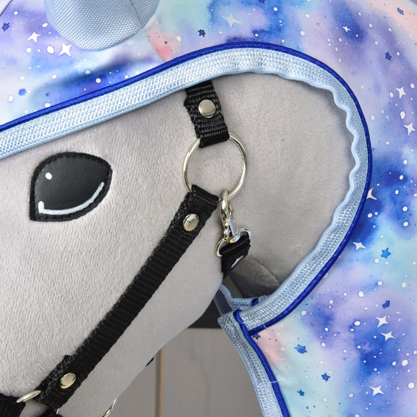 Detail hlavy plyšového koně v černé uzdečce a výrazném hvězdném obalu se vzorem Space v kombinaci s Hobby Horse LarDen Pláštěnka Space – ideální pro představení stylových doplňků pro Hobby Horse za každého počasí.