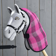 Šedý Hobby Horse od Hobby Horse LarDen s černou uzdečkou a dekou Deka stájová Pink, na dřevěné tyči, před šedou dřevěnou stěnou.