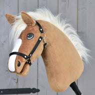 Hobby Horse Star s černou ohlávkou od Hobby Horse LarDen, s karamelovou srstí, bílou hřívou a černou uzdečkou, na šedém dřevěném pozadí.