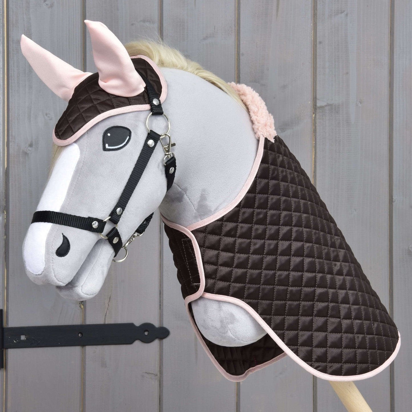 Hobby Horse LarDen Set Thermo Sweety s plyšovým Hobby Horse s uzdečkou, oblečeným do prošívané hnědo-růžové deky a ladící čabraky, vystavený na dřevěném pozadí.
