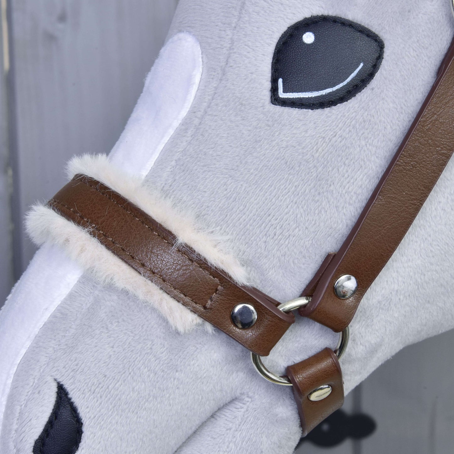 Detail obličeje šedého plyšového koně s vyšívanýma černýma očima a nosem, který má na sobě Ohlávku s beránkem z koženky Walnut od Hobby Horse LarDen s nadýchanou krémovou podšívkou u přezky.