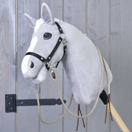 Šedý plyšový Hobby Horse od Hobby Horse LarDen s Westernovými otěžemi Dallas rozdělenými a černou uzdečkou, nasazený na dřevěné tyči před šedou dřevěnou stěnou.