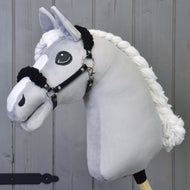 Černá ohlávka z koženky s černým beránkem od Hobby Horse LarDen na plyšovém světle šedém koni s černou koženkovou ohlávkou a velkýma vyšívanýma očima, před šedým dřevěným pozadím.