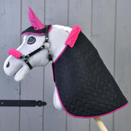 Set Thermo Pinkie (čabraka + deka + ohlávka s beránkem) od Hobby Horse LarDen obsahuje šedého Hobby Horse s černou dekou s růžovým lemováním, ladící růžovou čabrakou a ohlávkou s beránkem, zobrazeného na dřevěném pozadí.
