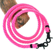 Otěže Pink od Hobby Horse LarDen, zářivě růžové pletené lano s černými kovovými karabinami na obou koncích, stočené na větvi stromu, ideální jako otěže pro Hobby Horse.